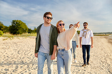 Image showing happy friends walking along summer beach