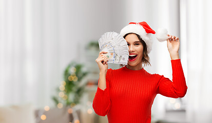 Image showing happy woman in santa hat with money on christmas