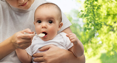 Image showing close up of mother with spoon feeding little baby