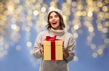 Image showing young woman in winter hat holding christmas gift