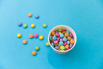 Image showing candy drops in paper cup on blue background