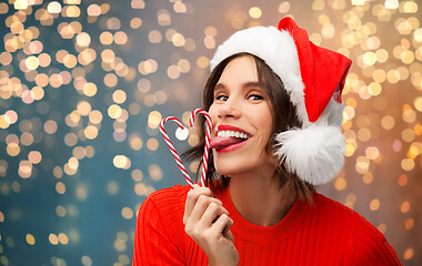 Image showing woman in santa hat licks candy canes on christmas