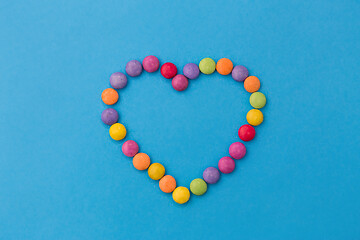 Image showing candy drops in shape of heart on blue background