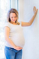 Image showing Beautiful pregnant woman standing near window at home in light interior