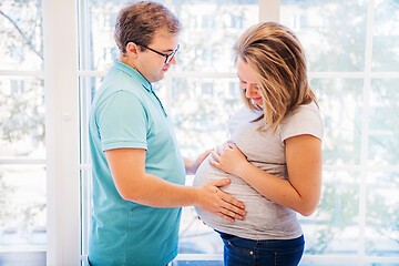 Image showing Beautiful pregnant woman and man sitting near wall