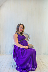 Image showing Beautiful pregnant woman in ultra violet dress sitting on the armchair