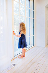 Image showing Cute girl in casual clothes standing near the window and watching out