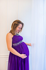 Image showing Beautiful pregnant woman in ultra violet dress standing near window