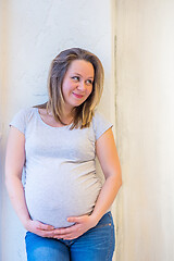 Image showing Beautiful pregnant woman standing near window at home in light interior