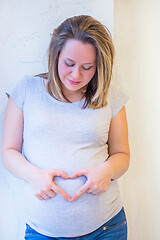 Image showing Beautiful pregnant woman standing near window at home in light interior