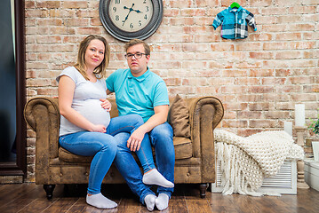 Image showing Beautiful pregnant woman and man sitting near wall