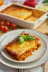 Image showing Homemade tasty meat lasagna with fresh basil and parmesan cheese in a plate on wooden background