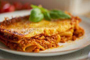 Image showing Homemade tasty meat lasagna with fresh basil and parmesan cheese in a plate on wooden background