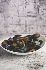 Image showing Fresh and raw sea mussels in white ceramic bowl on stone background