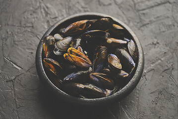 Image showing Fresh and raw sea mussels in black ceramic bowl placed on dark s