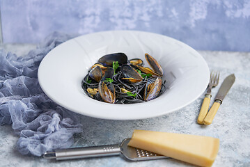 Image showing Black seafood spaghetti pasta with mussels over stone background. Mediterranean delicious food