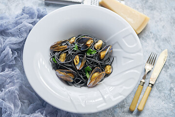 Image showing Black seafood spaghetti pasta with mussels over stone background. Mediterranean delicious food