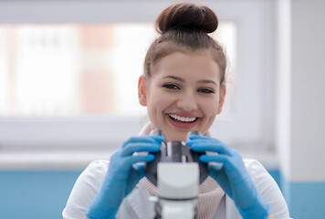 Image showing female student scientist looking through a microscope