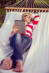 Image showing woman using a tablet computer while relaxing on hammock