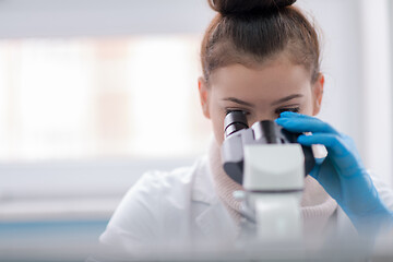 Image showing female student scientist looking through a microscope