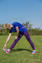 Image showing female runner warming up and stretching