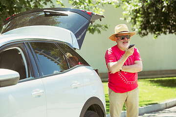 Image showing Senior man standing near by his car is working outdoors