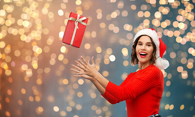 Image showing happy young woman in santa hat catching gift box