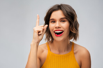 Image showing happy smiling young woman pointing finger up