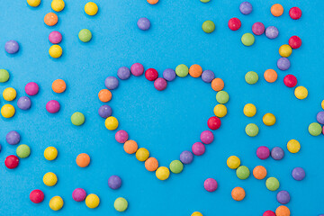 Image showing candy drops in shape of heart on blue background