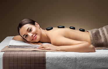 Image showing smiling woman having hot stone massage at spa