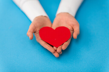 Image showing hands holding red heart shape on blue background