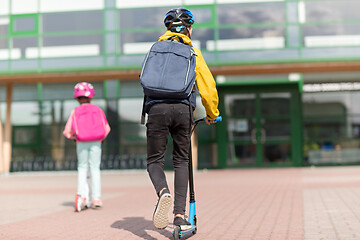 Image showing school children with backpacks riding scooters