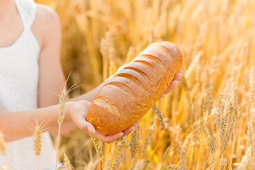 Image showing hands holding loaf of white bread on cereal field