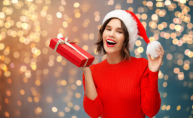 Image showing happy young woman in santa hat with red gift box