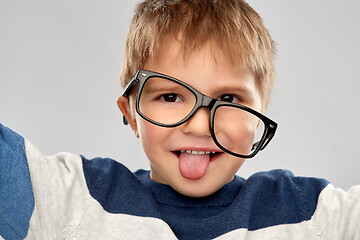 Image showing portrait of little boy in glasses showing tongue