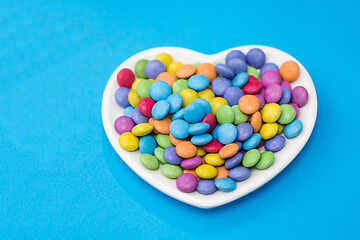 Image showing candies on heart shaped plate over blue background
