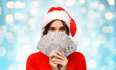 Image showing happy woman in santa hat with money on christmas