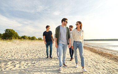 Image showing happy friends walking along summer beach