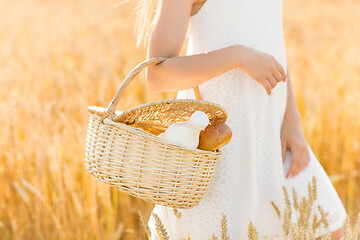 Image showing girl with bread and milk in basket on cereal field