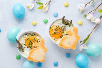 Image showing Shirred eggs (Oeuf cocotte) or baked eggs with green asparagus with Easter bunny and eggs