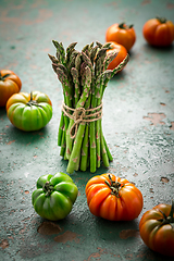 Image showing Assortment of organic tomatoes and green asparagus on old kitchen table