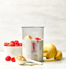 Image showing fresh banana, berries and milk in blender container 