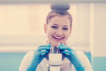 Image showing female student scientist looking through a microscope