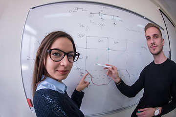 Image showing students writing on the white chalkboard