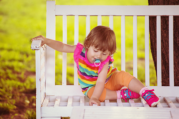 Image showing cute little girl sitting on wooden bench