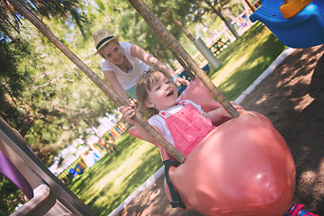 Image showing mother and daughter swinging in the park