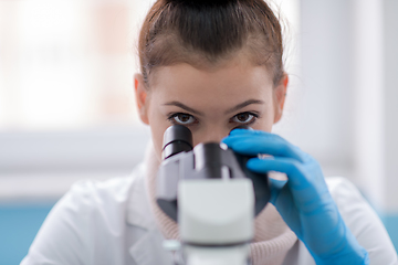 Image showing female student scientist looking through a microscope