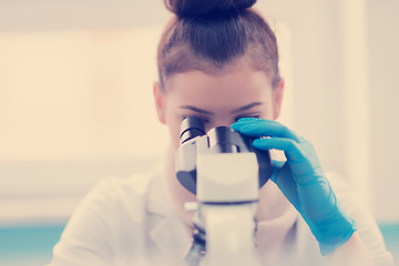 Image showing female student scientist looking through a microscope