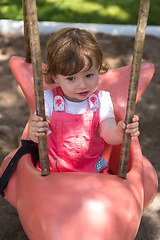 Image showing little girl swinging  on a playground