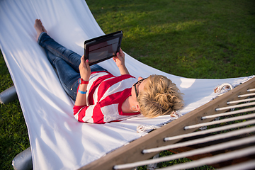 Image showing woman using a tablet computer while relaxing on hammock